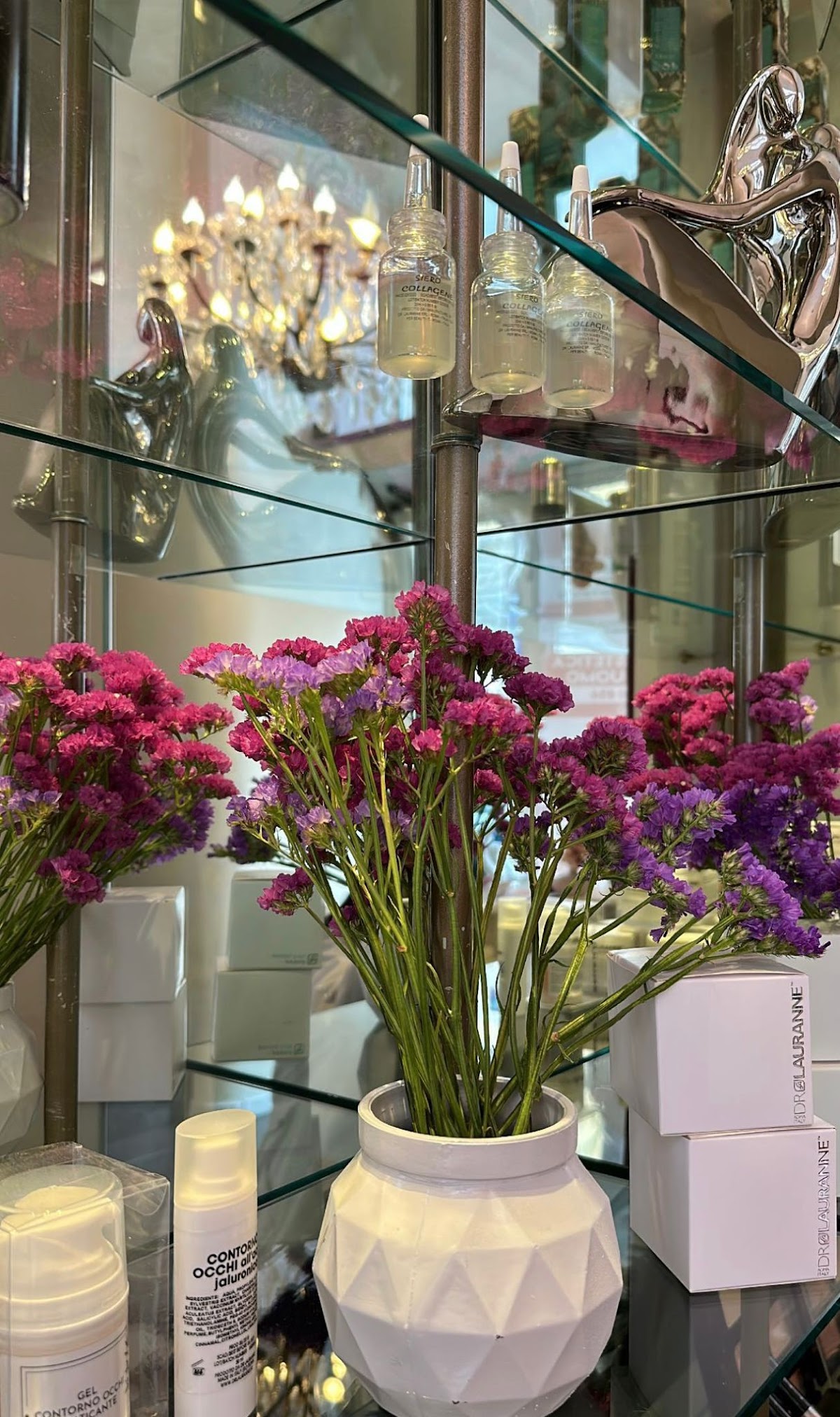 Composizione di fiori e profumatori d'ambiente su mensola a specchio